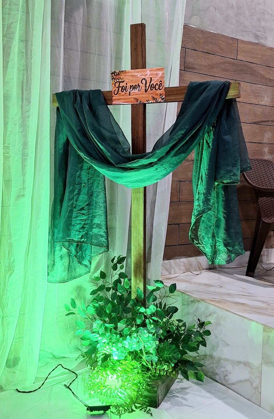 Cruz ornamentada com tecido verde e folhagens