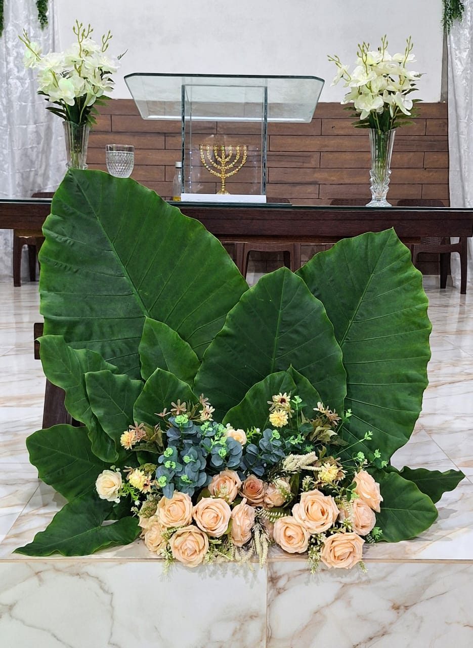 Arranjo de folhagens e rosas aos pés do altar
